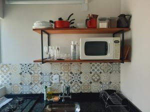 a kitchen with a sink and a microwave on a wall at Vila das Cachoeiras in Brotas