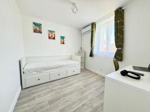 Un dormitorio blanco con una cama y un escritorio. en Séjour magique proche aéroport CDG Astérix Disney et Paris Maison toutes commodités, terrasse, WIFI, CLIM, lave vaisselle, en Saint-Mard