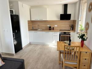 Una cocina con gabinetes blancos y una mesa de madera. en Séjour magique proche aéroport CDG Astérix Disney et Paris Maison toutes commodités, terrasse, WIFI, CLIM, lave vaisselle, en Saint-Mard