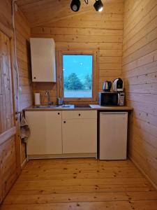 een keuken in een blokhut met een wastafel en een magnetron bij Domki Gajewo 2 in Gajewo +2 foto's