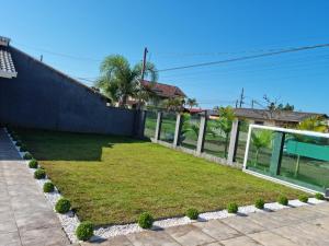 a backyard with a lawn and a fence at Casa Alto Padrão Perto da Praia C/ Piscina Grande in Guaratuba