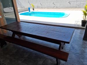 a wooden bench sitting in front of a swimming pool at Casa Alto Padrão Perto da Praia C/ Piscina Grande in Guaratuba