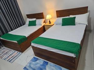two beds in a small room with green sheets at Hills Kandy Apartment in Kandy