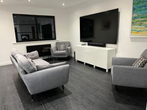 a living room with two chairs and a flat screen tv at Art Deco 52 in Truro