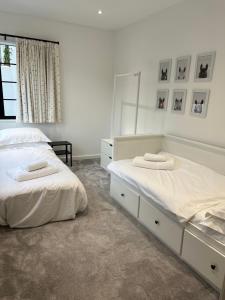 two beds in a bedroom with white walls at Art Deco 52 in Truro