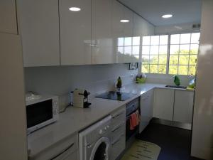 a kitchen with white cabinets and a sink and a dishwasher at Gavá Vila Blanxe in Gavà