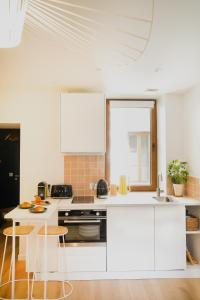 a kitchen with white cabinets and a table and chairs at Le Cocon d'Alice - Cosy, calme, central et climatisé in Annecy