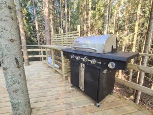 a grill on a wooden deck next to a tree at Glampingtält i naturen in Molkom