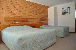 a bedroom with two beds and a brick wall at Keith Motor Inn in Keith