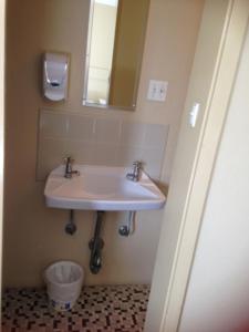 a bathroom with a sink and a mirror at Hotel Beach House Nambour in Nambour