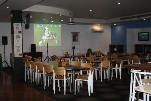 a dining room with tables and chairs and a screen at Hotel Beach House Nambour in Nambour