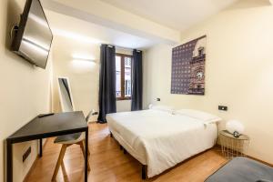 a bedroom with a bed and a desk and a clock on the wall at Emilia Studios in Modena