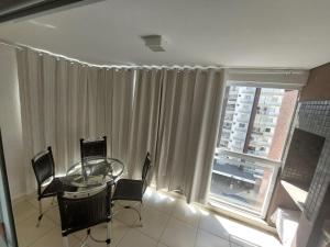 a dining room with a glass table and a window at Apartamento 704-C Casa da Madeira Caldas Novas in Caldas Novas