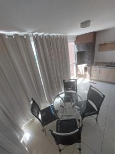a glass table and chairs in a room with a window at Apartamento 704-C Casa da Madeira Caldas Novas in Caldas Novas