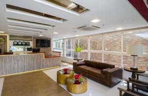 a lobby with a leather couch and a bar at Profissionalle Hotel São Luís in São Luís