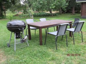 a grill and a picnic table with chairs around it at Maatilamajoitus in Ylihärmä