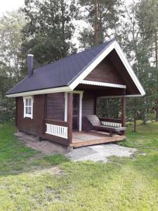 a small cabin with a porch in the grass at Maatilamajoitus in Ylihärmä