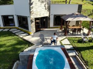a man sitting in a chair next to a swimming pool at Casa Bella Guatapé acceso directo a la represa in Guatapé