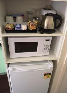 a white microwave sitting on top of a refrigerator at Winchester Motel in Moree