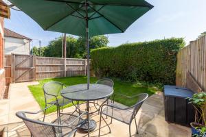 a table with chairs and an umbrella on a patio at Rambler’s Retreat in Dersingham +17 photos