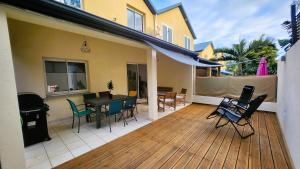 a patio with a table and chairs on a deck at Maison Calme aux Avirons in Les Avirons