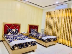 two beds in a room with yellow walls and curtains at Guest House near islamabad airport in Islamabad