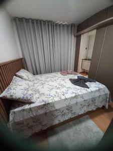 una piccola camera da letto con un letto con copriletto floreale di Apto Novo Próx Shopping Poços MG a Poços de Caldas
