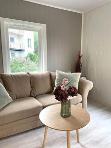 a living room with a couch and a table with flowers at 2 etasje leilighet med 2 soverom in Harstad