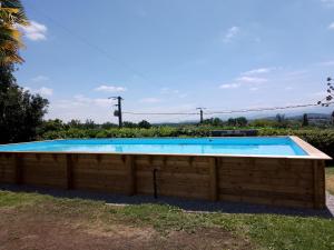a large swimming pool with a wooden wall at Pyrenees Vue Gite - Vues Fantastique, Parking Gratuit Sur Place & Piscine in Saint-Gaudens