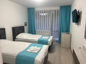 a hotel room with two beds and a television at Хотел Лилия in Rudozem