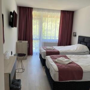 a hotel room with two beds and a television at Хотел Лилия in Rudozem +3 photos