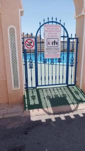 een blauwe poort voor een gebouw met een bord bij Bungalow Playa Flamenca in Orihuela