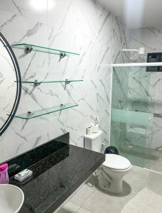 a bathroom with a toilet and a glass shower at Casa Primavera aluguel temporada in Paripueira