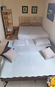 duas camas em um quarto com lençóis e travesseiros brancos em Apartamento com ar-condicionado em Salvador mais 15 fotografias