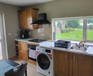 eine Küche mit einer Waschmaschine und einem Waschbecken in der Unterkunft Lake lodging Dungloe 1 mile from Dungloe, 2bdrm max3 adults in Dungloe