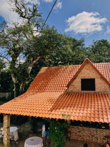 a building with an orange roof with tables and chairs at Chalé Suíça da Serra in São Benedito