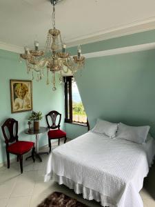 a bedroom with a bed and chairs and a chandelier at Chalé Suíça da Serra in São Benedito