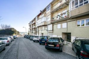 a row of cars parked on a street next to a building at WHome Peaceful Algés Family Home away from City Noise in Algés