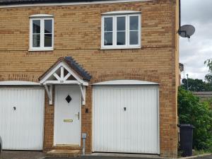 ein Backsteinhaus mit zwei weißen Garagentoren in der Unterkunft Landau House in Bristol
