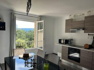eine Küche mit Esstisch und großem Fenster in der Unterkunft Bel appart - 3 ch Vallon pont d 'arc in Salavas