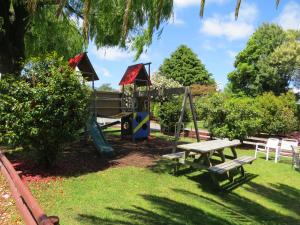 een park met een bank en een speeltuin bij Camellia Court Family Motel in Taupo