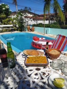 een tafel met eten en drinken naast een zwembad bij Villa das Pedras - Ponta de Pedras in Goiana