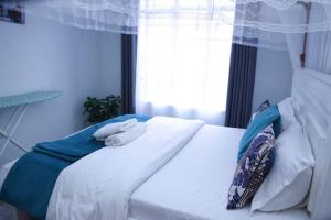 a bedroom with a white bed with towels on it at Furnished 1BR Embakasi by LaMeg in Nairobi