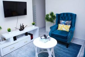a living room with a blue chair and a tv at Furnished 1BR Embakasi by LaMeg in Nairobi