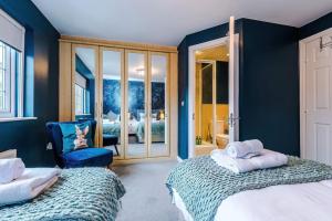 a bedroom with two beds and a blue wall at Luxury 3-bed house - Rothwell Gardens - 10mins from Leeds city centre in Rothwell