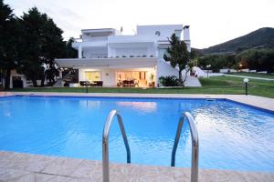 a villa with a swimming pool in front of a house at La Maison Blanche in Kavala