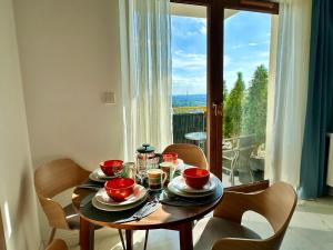 a wooden table with plates and bowls on it in front of a window at Vidok Residence Apartments in Młoszowa