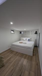 Habitación blanca con cama grande y suelo de madera. en *J'y suis j'y reste* - proche de Paris, en Villejuif