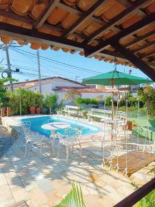 een terras met een tafel en stoelen en een zwembad bij Villa das Pedras - Ponta de Pedras in Goiana