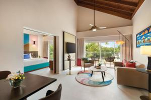 a living room with a couch and a table and a bed at Secrets La Romana All-Inclusive Adult Only Resort & Spa in Bayahibe